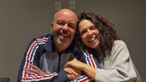 Alex Escobar aparece ao lado de uma mulher em foto descontraída, ambos sorrindo, em registro divulgado no Instagram @alexescobar74. Após cirurgia, Alex Escobar atualiza estado de saúde.