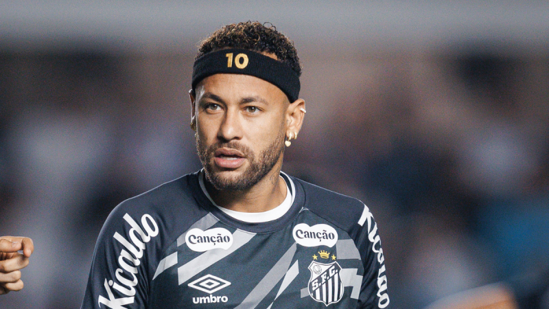 Neymar em imagem de partida, com faixa no cabelo e camisa do Santos FC, encarando a câmera em estádio desfocado ao fundo. Foto esportiva