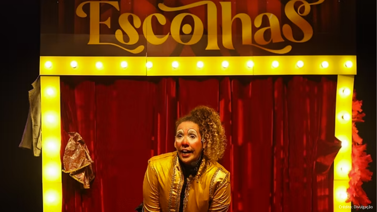 Palco de circo com cortina vermelha, luzes amarelas em volta e um artista vestido com casaco dourado e expressão animada diante da plateia.