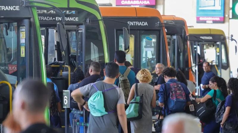 Fim da escala 6x1: passageiros aguardam e entram em ônibus urbanos em terminal de transporte, com equipes e pessoas organizadas para embarque.