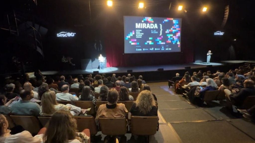Abertura da 8ª edição do Mirada no Sesc Santos, com plateia sentada em auditório e telão exibindo a programação do evento.