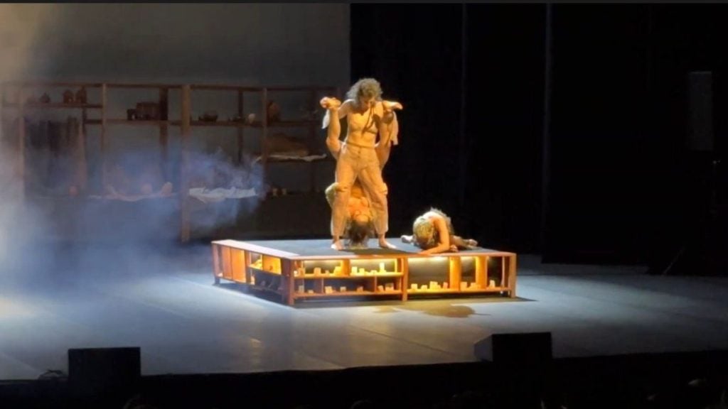 Mirada: cena de teatro na abertura da 8ª edição, com dois artistas sobre um palco iluminado, fumaça e cenário ao lado, no Sesc Santos.