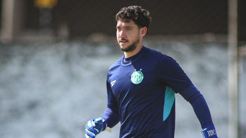 Caíque França Guarani: Goleiro do Guarani em campo, usando uniforme azul e luvas, em momento de concentração durante treino ou partida, enquanto rebate acusações e desabafa sobre polêmicas