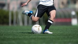Jogador de futebol em campo chutando a bola, com foco na partida; imagem ilustrativa sobre onde assistir ao Brasileirão e os jogos da 26ª rodada.