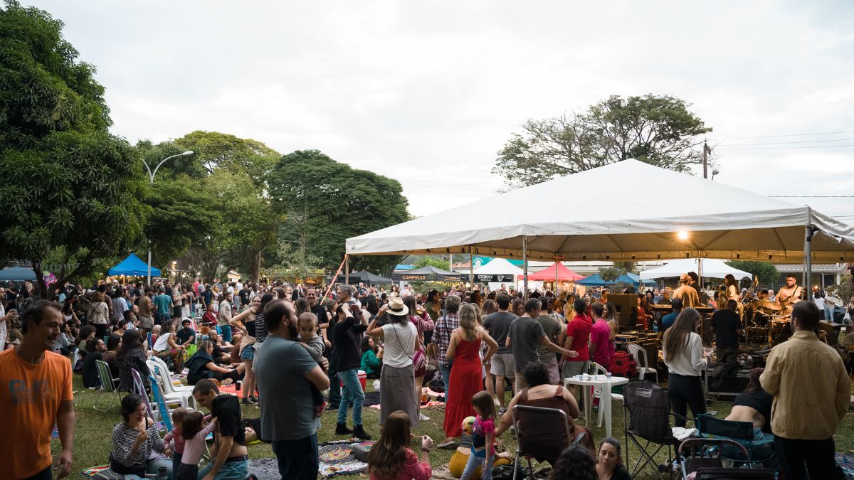 Público reunido em festival da cerveja de Barão, com barracas e tendas ao ar livre, pessoas conversando e a área do evento lotada ao fim da tarde.