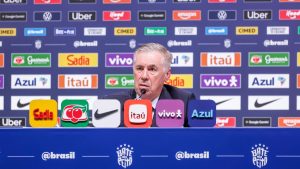 Convocação da Seleção Brasileira: Carlo Ancelotti fala em coletiva de imprensa na CBF, com painéis de patrocinadores ao fundo e microfone à frente; horário e onde assistir ao vivo.