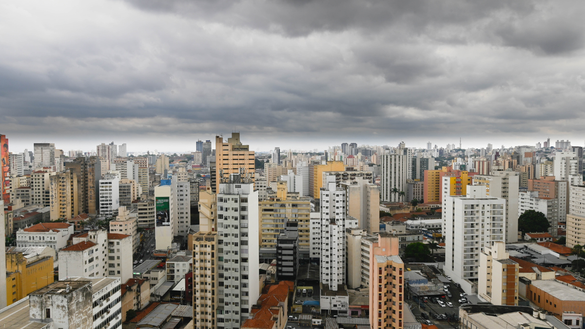 Vista panorâmica de Campinas com prédios residenciais e comerciais altos, ruas entre os edifícios e céu nublado ao fundo