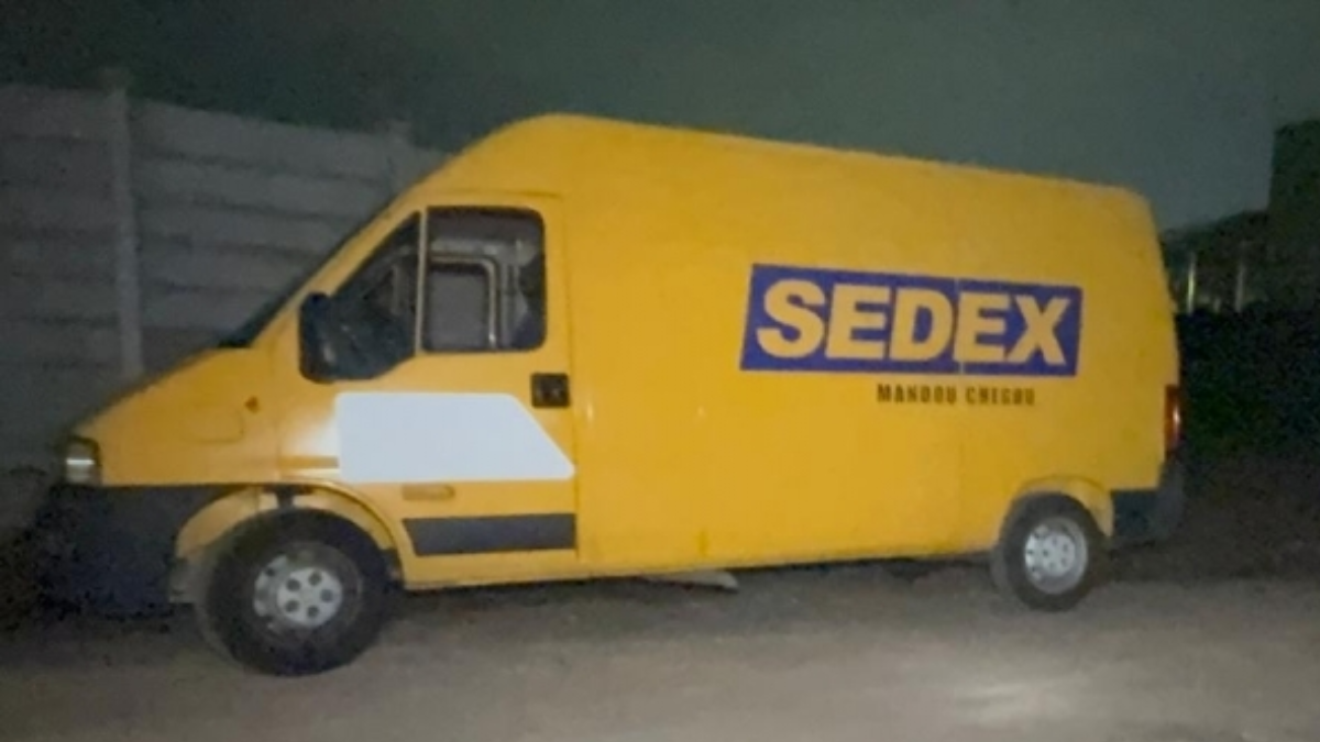 caminhão dos correios roubado por criminosos: Caminhão dos Correios “SEDEX” amarelo em via escura, com criminosos armados em cena de roubo na Rodovia Anhanguera, enquanto o caminhão é tomado por criminosos