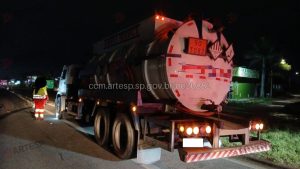 Homem morre atropelado em Rodovia de Itanhaém: Caminhão-tanque em rodovia à noite após acidente, com cones e veículos parados, cena de emergência na estrada de Itanhaém. Motoristas fogem após atropelamento.