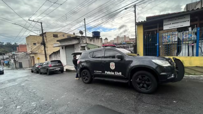 Viatura da Polícia Civil estacionada na rua em frente a um prédio comercial, em operação de investigação sobre esquema de lavagem de dinheiro.