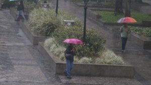 Chuva forte em Santos, com pessoas caminhando em meio a grande volume de água e guarda-chuvas durante o período que registrou 203,1 mm de chuva em nove dias.