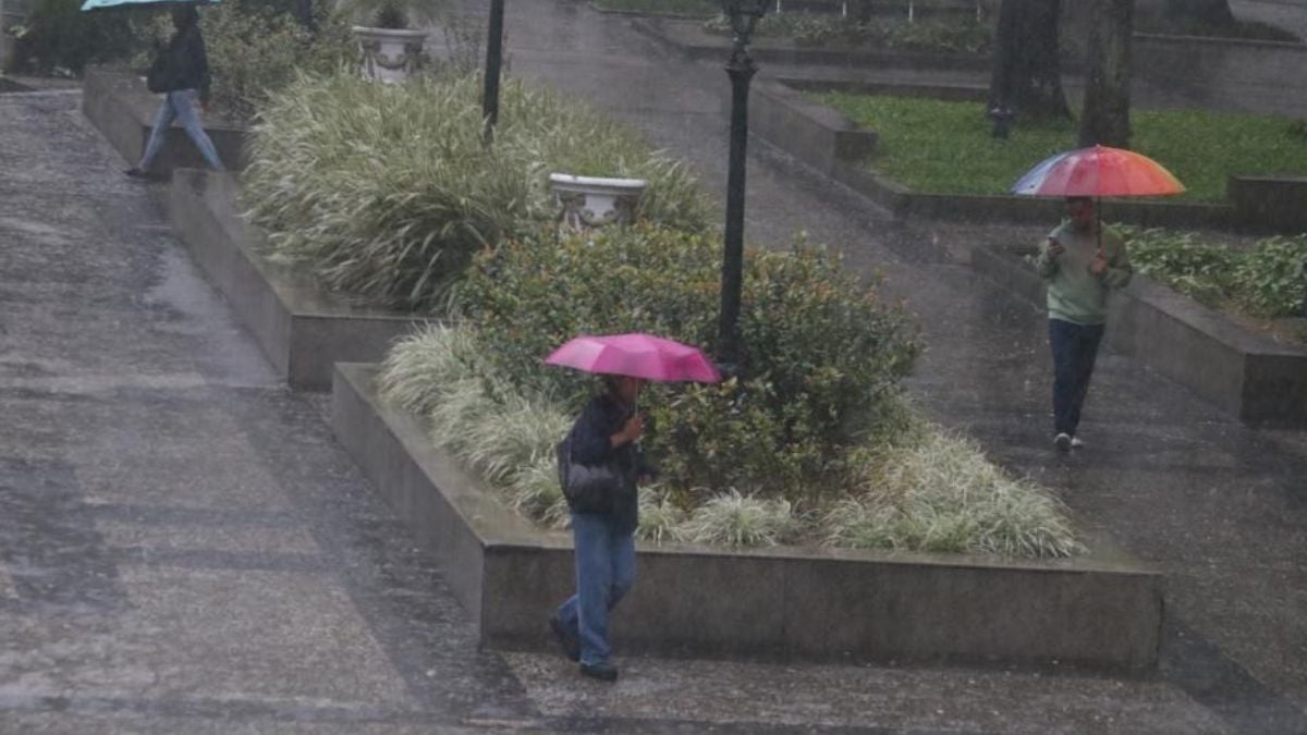 Chuva forte em Santos, com pessoas caminhando em meio a grande volume de água e guarda-chuvas durante o período que registrou 203,1 mm de chuva em nove dias.