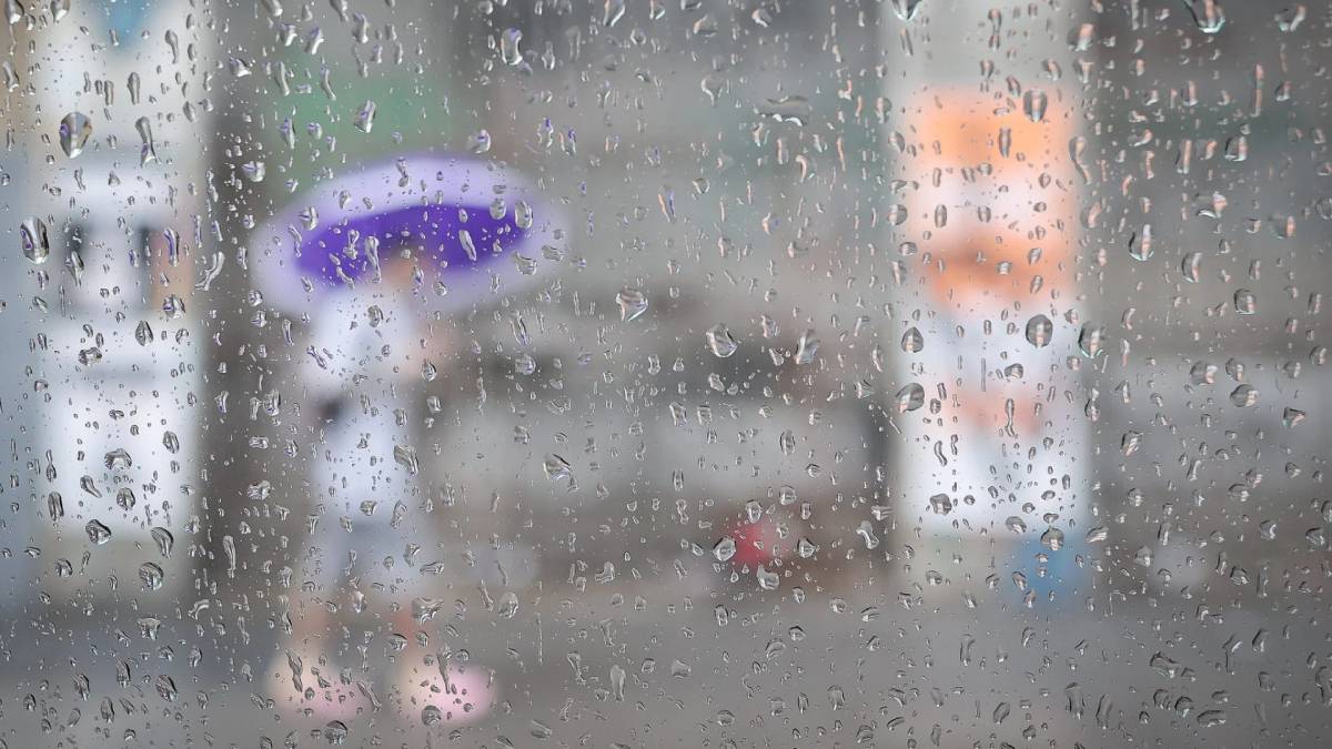 Chuva forte e ventos ao fundo vistos através de gotas na janela, transmitindo orientações de segurança para se proteger durante chuvas extremas e rajadas