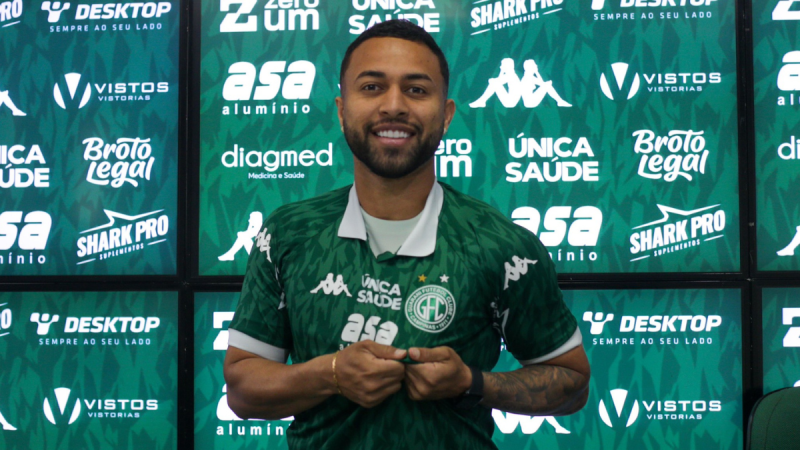 Gabriel Silva Justiça Guarani aparece em coletiva de imprensa com camisa do Guarani, em frente a um painel verde e marcas esportivas, posando sorridente.