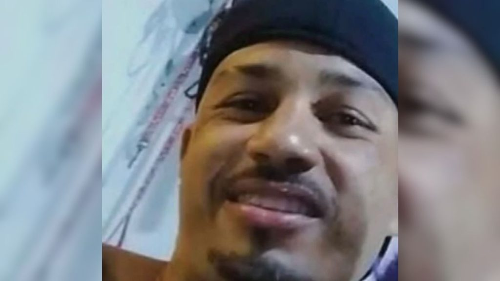 pais de motorista que matou coletor: Foto em close de um homem em ambiente externo, usando boné e expressão séria, em contexto de reportagem sobre acidente com ciclista em São Vicente — Foto: reprodução.