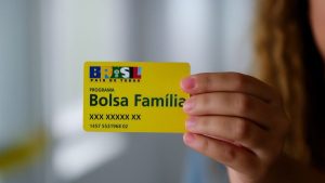 Calendário do Bolsa Família com cartão do programa na mão, mostrando a identificação “Bolsa Família”