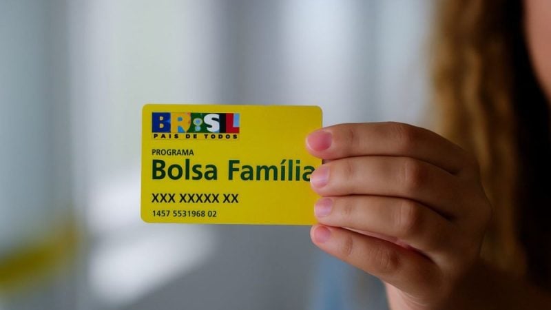 Calendário do Bolsa Família com cartão do programa na mão, mostrando a identificação “Bolsa Família”