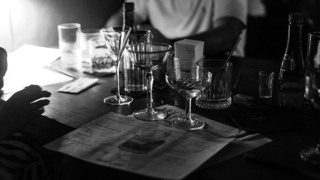 Negroni Week em Hideout Speakeasy: mesa com taças e copos de coquetéis em ambiente de bar, criando carta inspirada por clientes na Baixada Santista