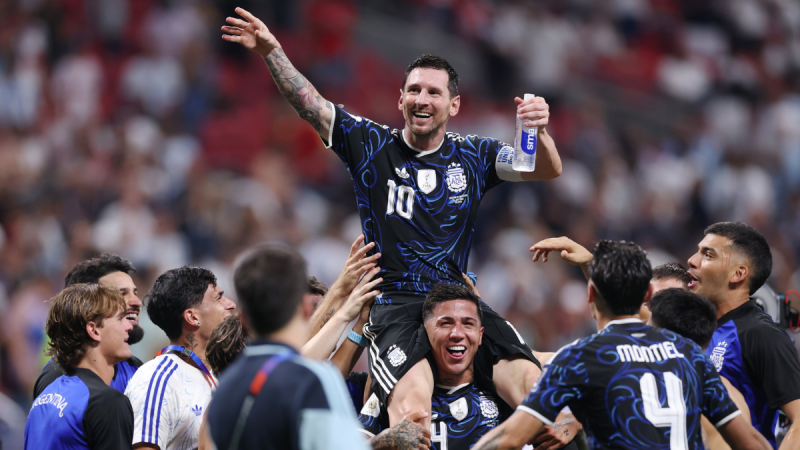 Messi Argentina em campo com a seleção, comemorando com braços erguidos e sorriso após marcar ou marcar presença em partida diante do público