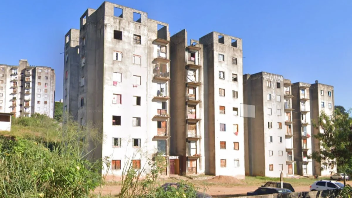 Incêndio em Campinas: prédios residenciais com janelas e varandas ao fundo, cenário urbano após ocorrências no bairro, com vegetação na frente e rua ao nível térreo.