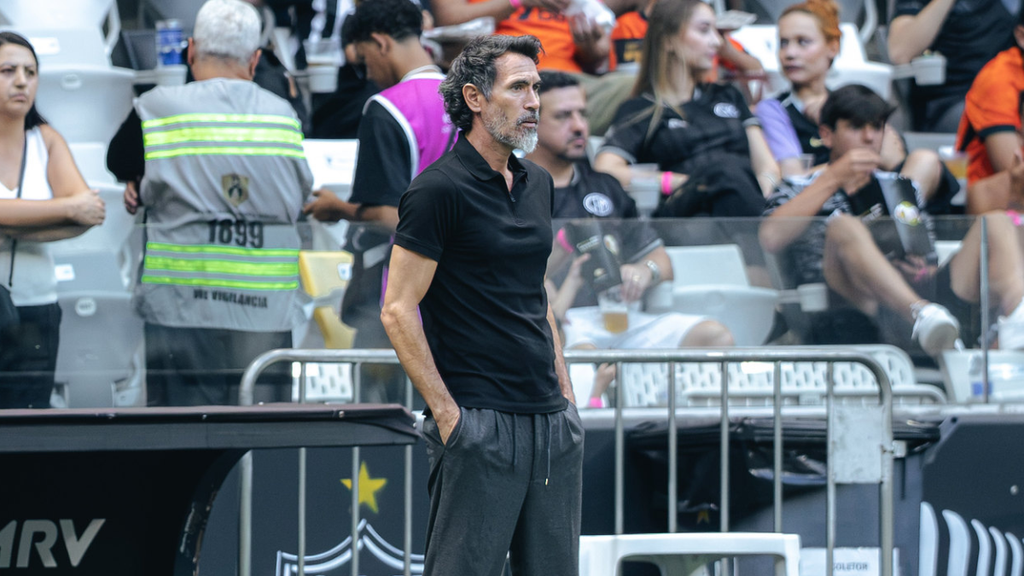 Neymar Atlético: Eduardo Domínguez, técnico do Atlético, aparece em pé na área técnica durante uma partida, olhando para o campo enquanto pessoas ao fundo acompanham o jogo. Foto: Pedro Souza / Atlético.