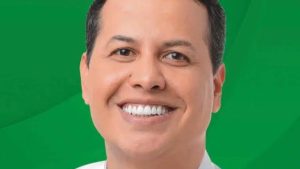Foto de Danilo Morgado, candidato a deputado, com fundo verde, sorrindo em imagem de divulgação. Notícia sobre quem é Danilo Morgado e sua prisão nesta quinta-feira.