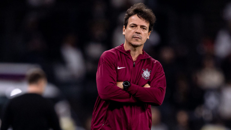 Fernando Diniz Corinthians: Fernando Diniz no treino do Corinthians, usando agasalho vermelho e braços cruzados em partida disputada no estádio