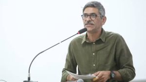 Vereador que caiu no Rio Piracicaba aparece em coletiva, falando ao microfone e segurando documentos, com expressão de seriedade, em imagem associada à melhora na UTI.