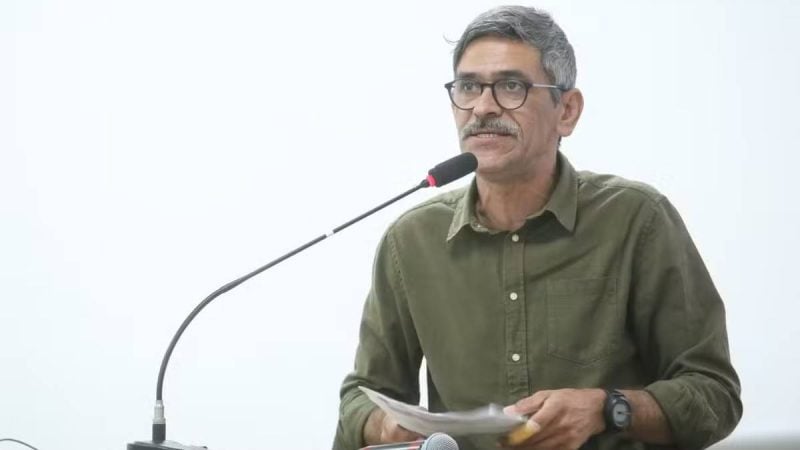 Vereador que caiu no Rio Piracicaba aparece em coletiva, falando ao microfone e segurando documentos, com expressão de seriedade, em imagem associada à melhora na UTI.