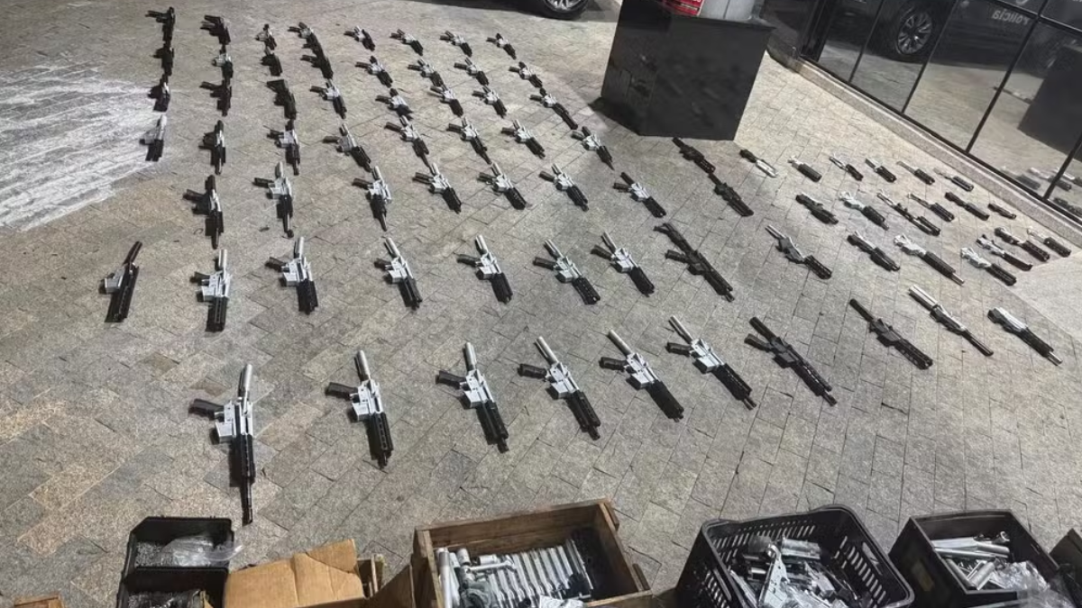 Fábrica clandestina de fuzis em Santa Bárbara: fotografia mostra dezenas de fuzis e peças de armas apreendidas sobre o chão de um ambiente investigado pela polícia