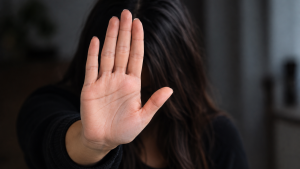 Mulher com a mão levantada em sinal de proteção e pedido de ajuda, cobrindo o rosto, reforçando o Sinal de socorro para violência doméstica e a comunicação silenciosa em Americana, interior de SP.