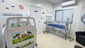 Quarto infantil hospitalar moderno, com berço aquecido e barreira protetora, porta e janelas amplas, piso claro e decoração lúdica nas paredes