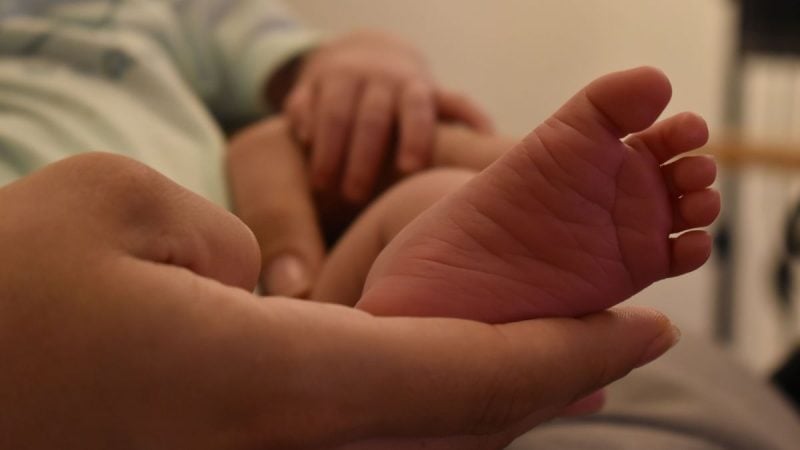 Mãos carinhosas segurando um bebê nos braços, em foto de banco para ilustrar o tema licença-maternidade e adotante após decisão do STF
