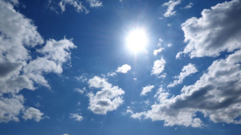 Céu azul com forte presença do sol entre nuvens, sugerindo calor extremo associado a El Niño no Brasil.