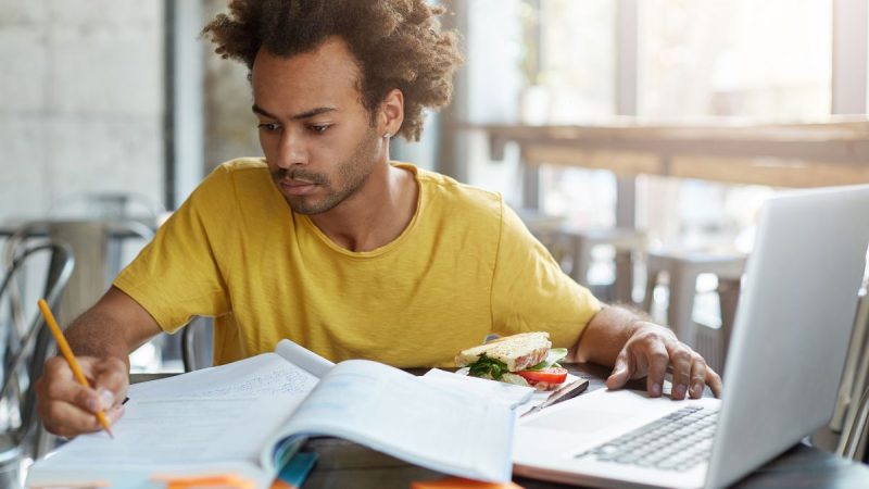 Enem: jovem estudando para o exame em uma mesa com caderno aberto, caneta e notebook, enquanto organiza anotações para estudar sem perder tempo antes da prova