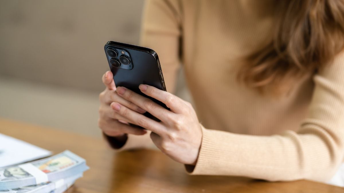 IA nas eleições 2026: mulher em ambiente doméstico usando celular, ilustrando como evitar golpes e conteúdos falsos com IA durante a campanha política.