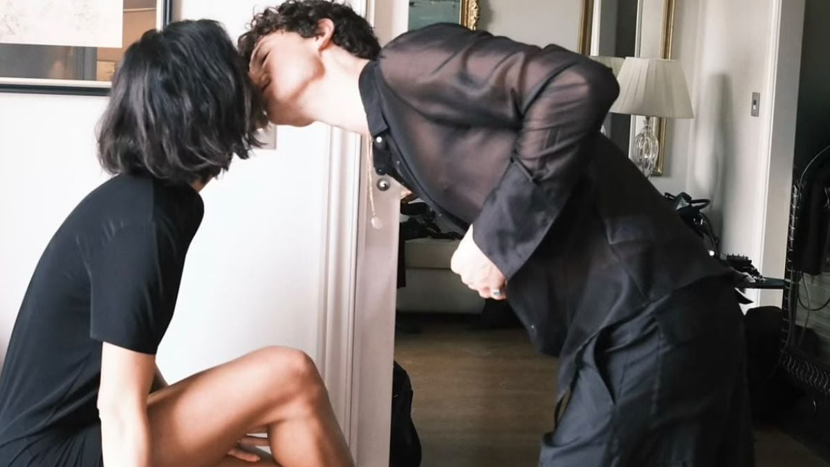 Shawn Mendes se abaixa para beijar Bruna Marquezine, que está sentada em poltrona.