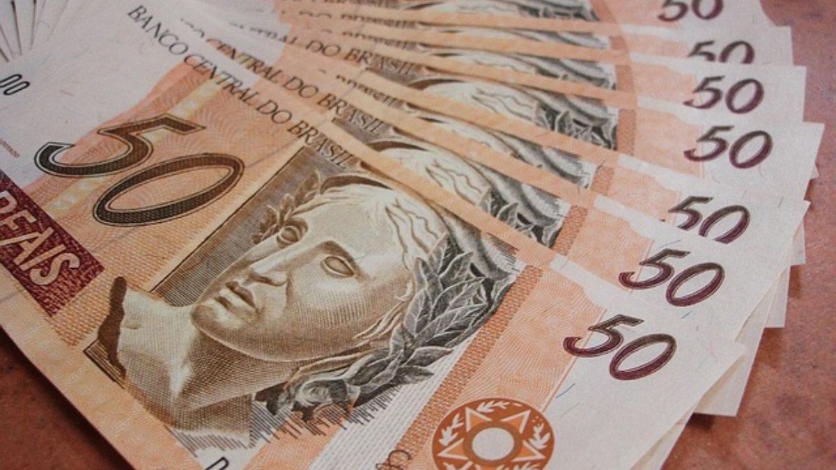 Notas de real empilhadas ao fundo, sugerindo crise financeira e impacto nas contas das famílias, com destaque para o dado: Inadimplência das famílias chega a 6%, maior nível da série histórica.