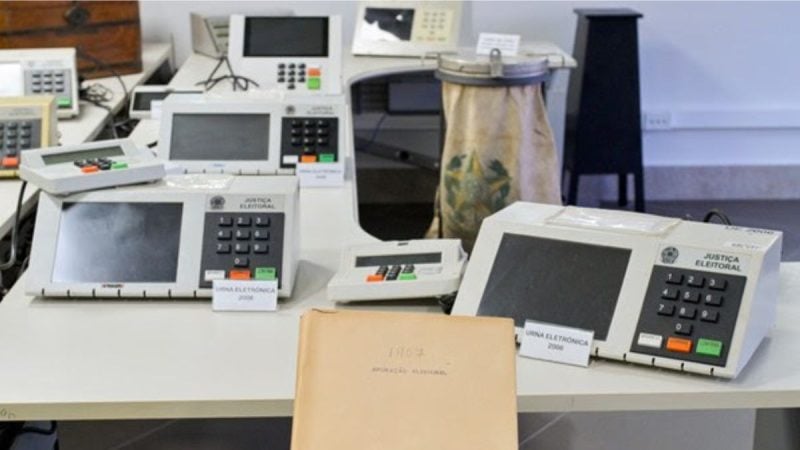 Laboratório com equipamentos eletrônicos e máquinas de teste sobre a bancada, incluindo analisadores e instrumentos de medição com telas e botões, em ambiente de pesquisa.