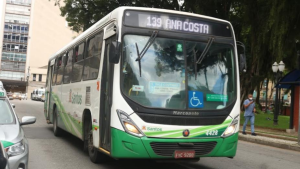 Ônibus urbano verde e branco da empresa em via urbana, com painel mostrando “139” e “SAO COSTA”, placa FVG 9288 e acessibilidade para cadeirante no para-brisa.