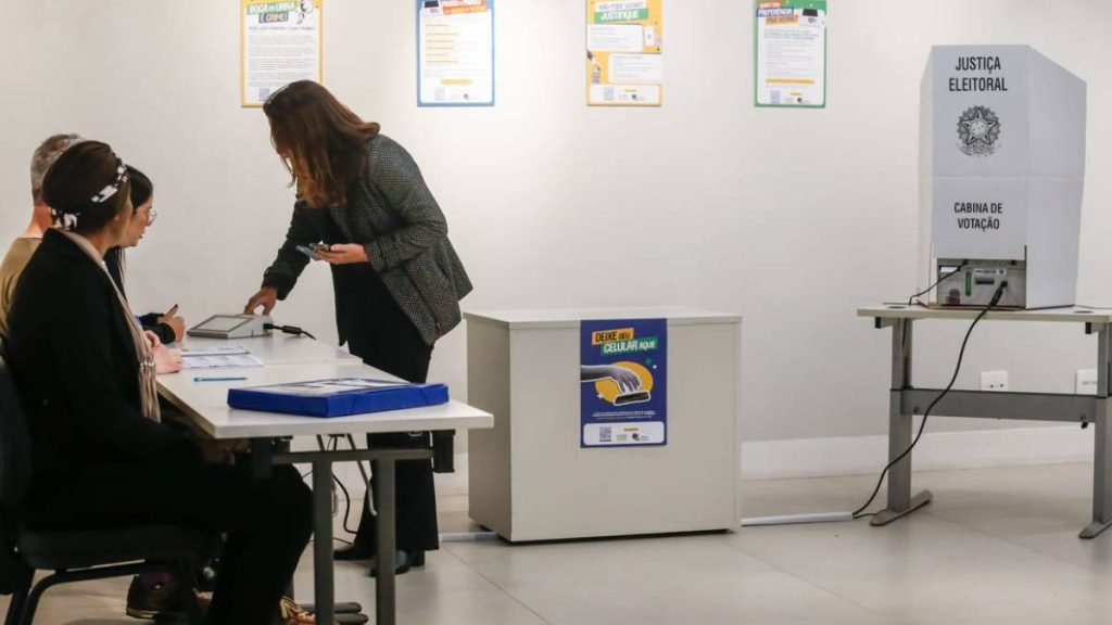 Eleitor consulta colinha de papel antes de votar na urna eletrônica