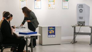 Eleitor consulta colinha de papel antes de votar na urna eletrônica