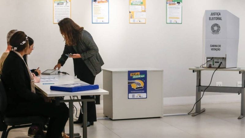 Eleitor consulta colinha de papel antes de votar na urna eletrônica