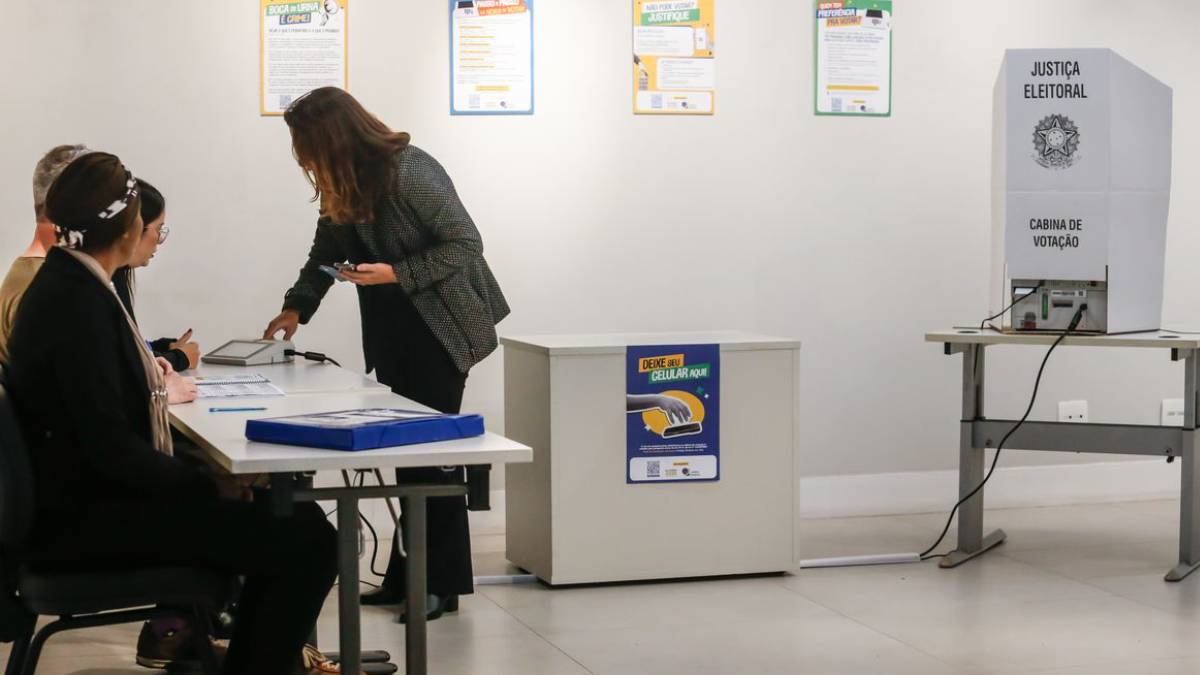 Eleitor consulta colinha de papel antes de votar na urna eletrônica