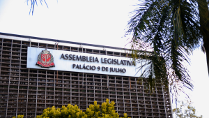 Fachada da Assembleia Legislativa no Palácio 9 de Julho, com a placa “ASSEMBLEIA LEGISLATIVA” e “PALÁCIO 9 DE JULHO” visível ao lado de janelas e da entrada do prédio.