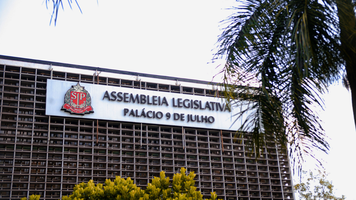 Fachada da Assembleia Legislativa no Palácio 9 de Julho, com a placa “ASSEMBLEIA LEGISLATIVA” e “PALÁCIO 9 DE JULHO” visível ao lado de janelas e da entrada do prédio.