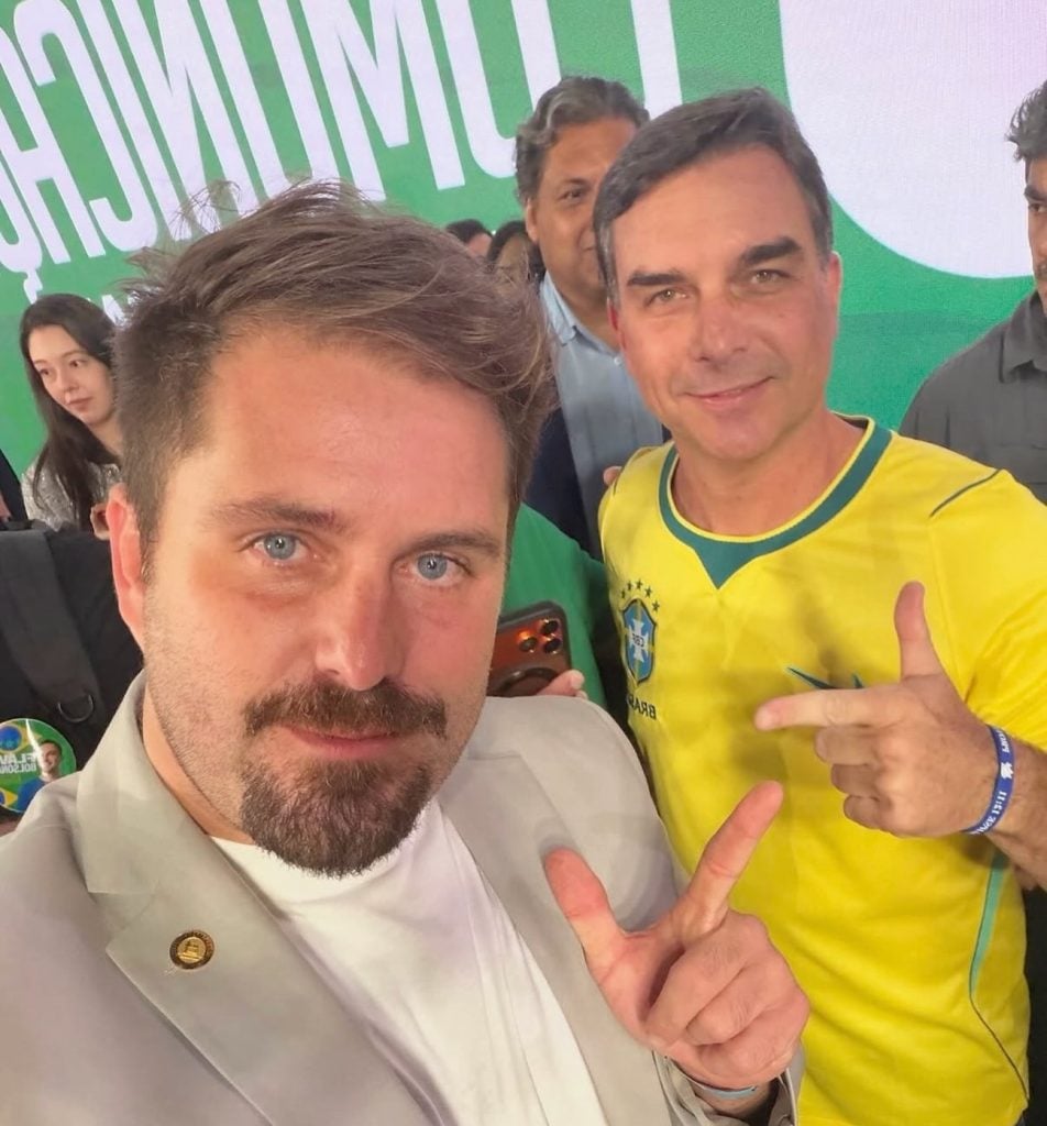 Thiago Gagliasso e Flávio Bolsonaro posam juntos durante evento.