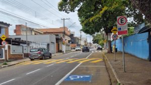Rua de Atibaia (SP) com faixa elevada, sinalização de trânsito, vaga de estacionamento para pessoa com deficiência e limite de velocidade de 30 km/h.
