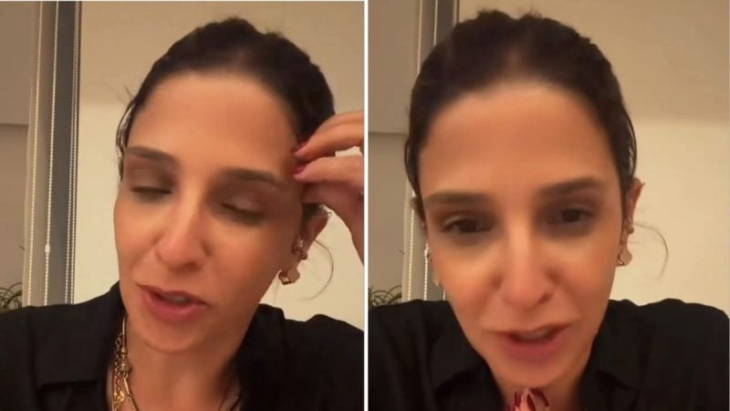 Ana Carolina Oliveira em close, com cabelo preso e brincos, em pose de selfie no quarto, fazendo uma expressão sorridente e falando para a câmera.