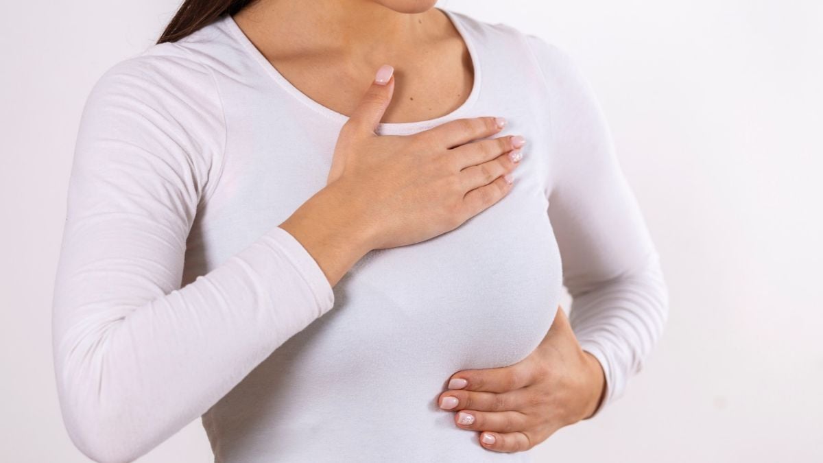 Câncer de mama: mulher com as mãos apoiando o peito, imagem sobre fisioterapia na recuperação antes e depois da cirurgia, em fundo claro.